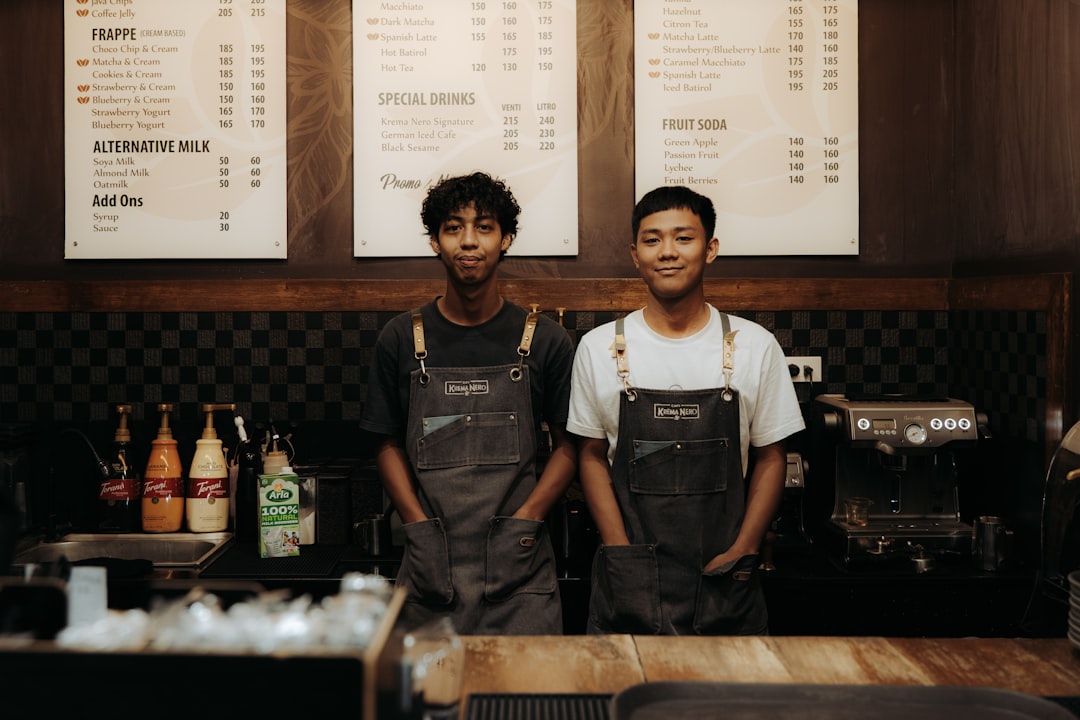 two-baristas-smiling-behind-a-counter-fduwaeewqt8